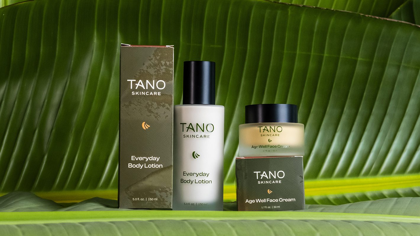 Tano Skincare Everyday Body Lotion and Age Well Face Cream packaging against banana leaves